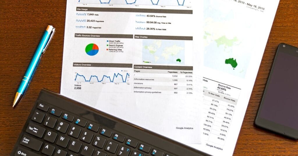 5 Strategi Marketing Berkesan untuk Bisnes SME dan Startup 5 Flatlay of a business analytics report, keyboard, pen, and smartphone on a wooden desk.