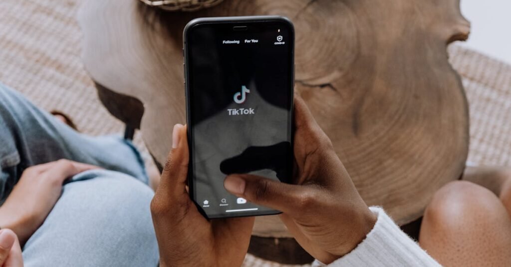 5 Tips Berkesan untuk TikTok Ads Malaysia 1 Close-up of hands holding a smartphone displaying the TikTok app interface on a wooden surface.